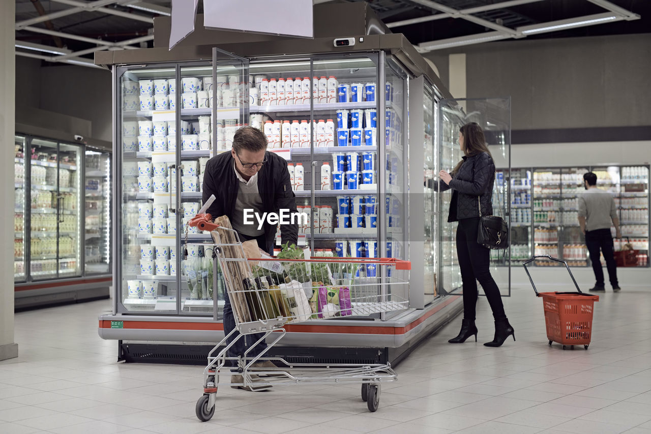 People buying groceries at refrigerated section in supermarket