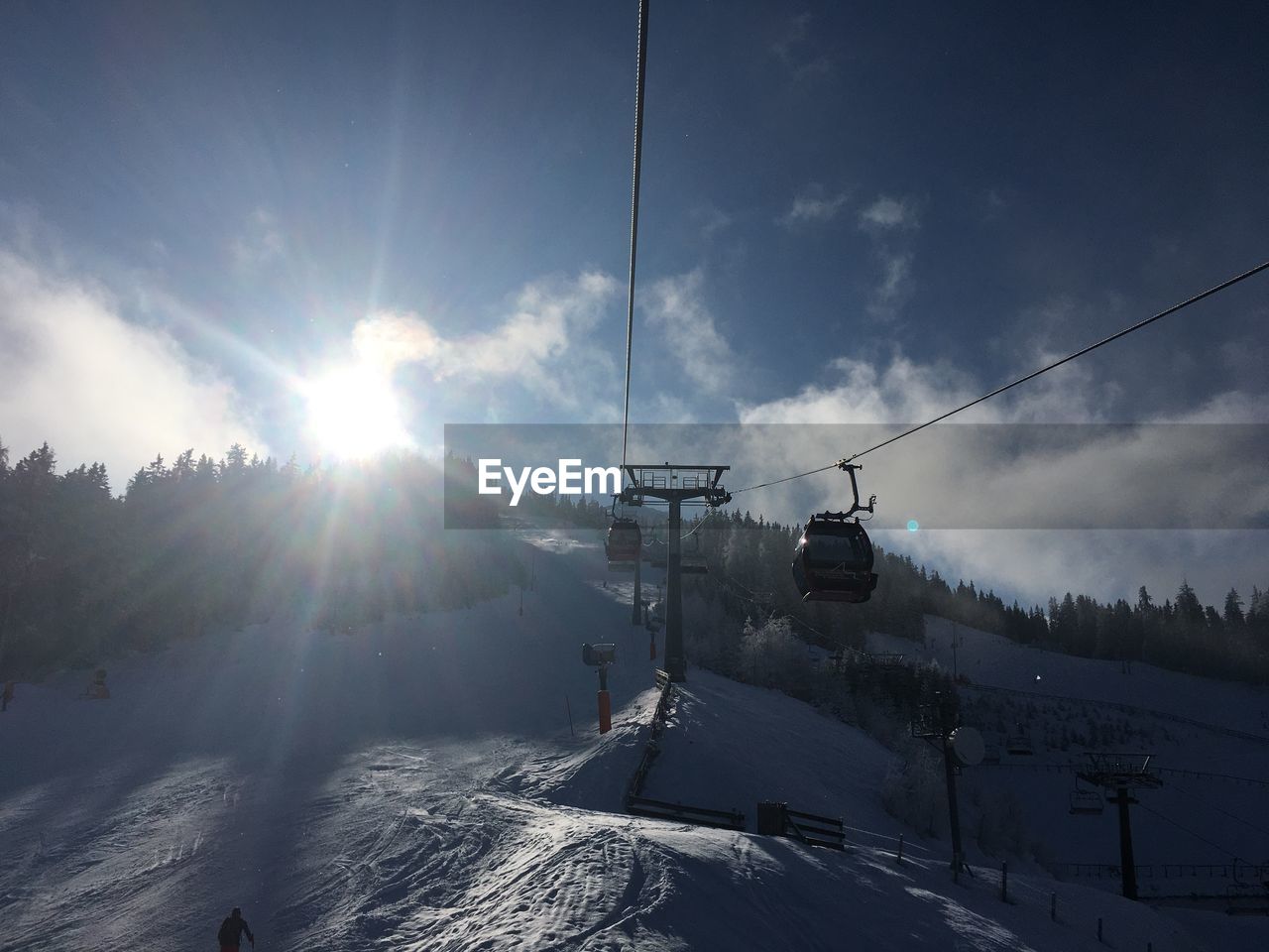 Ski lift over snowcapped mountains against sky on sunny day