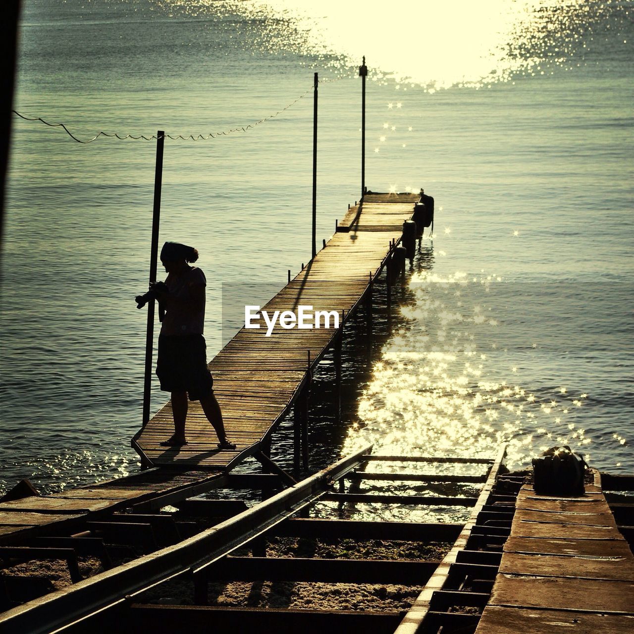 A photographer on a sunlit wooden pier