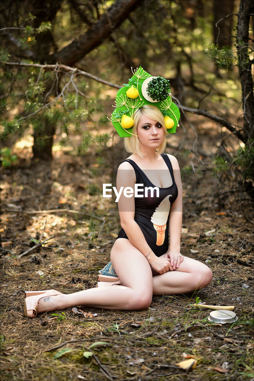Portrait of female model in swimwear sitting at forest