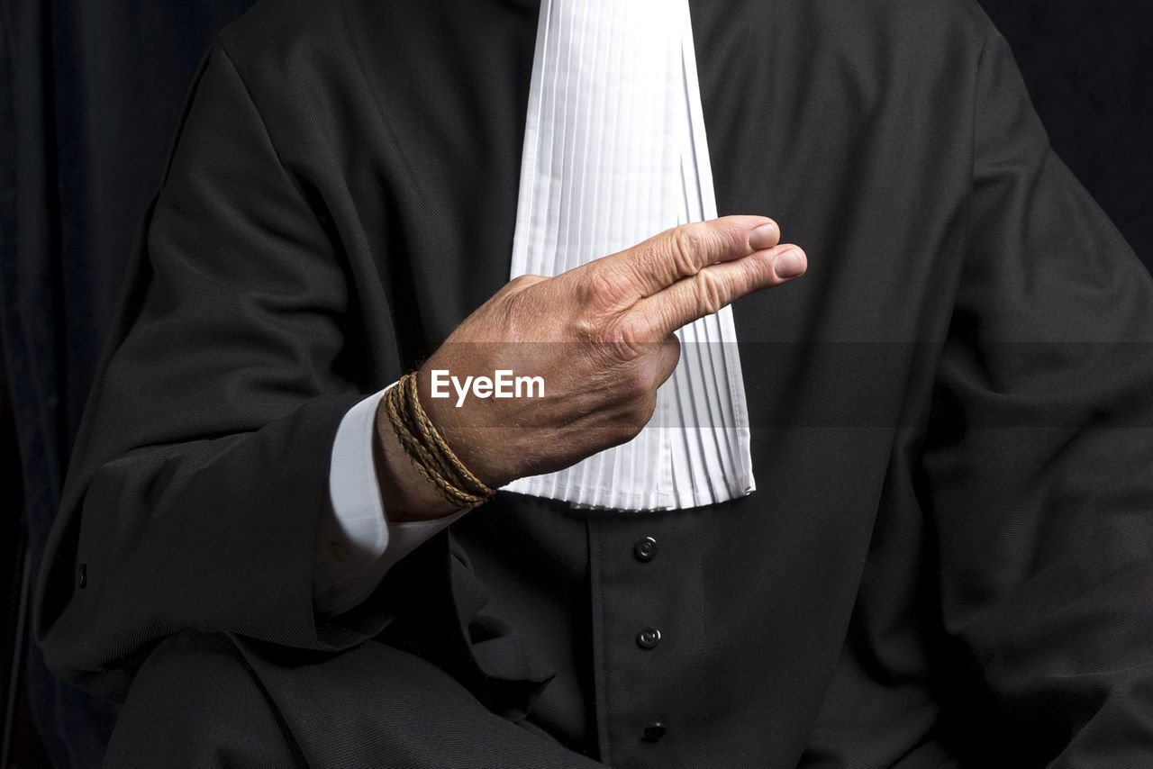 Midsection of lawyer gesturing against black background