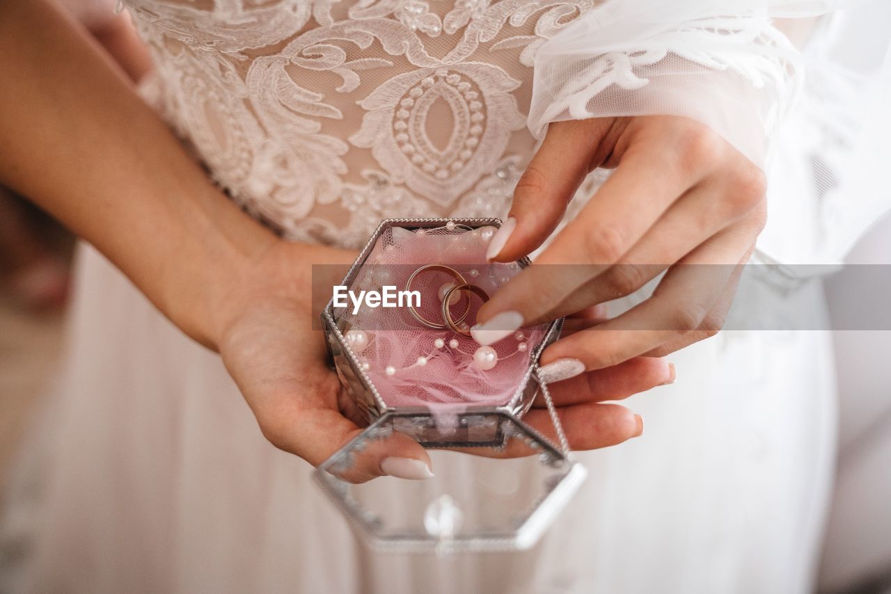 Midsection of bride holding rings in jewelry box during wedding ceremony 