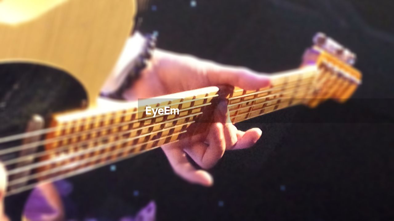 CROPPED IMAGE OF HAND PLAYING GUITAR