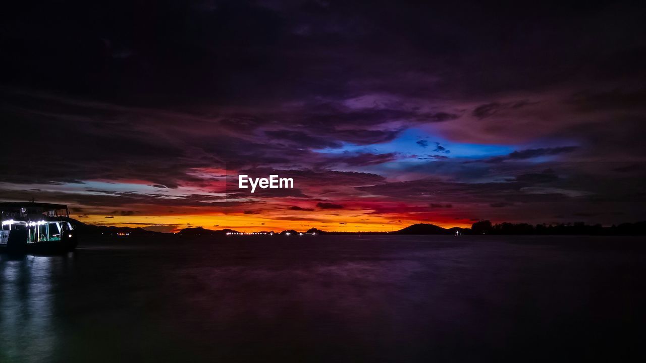 SCENIC VIEW OF DRAMATIC SKY OVER SILHOUETTE LANDSCAPE AGAINST SUNSET