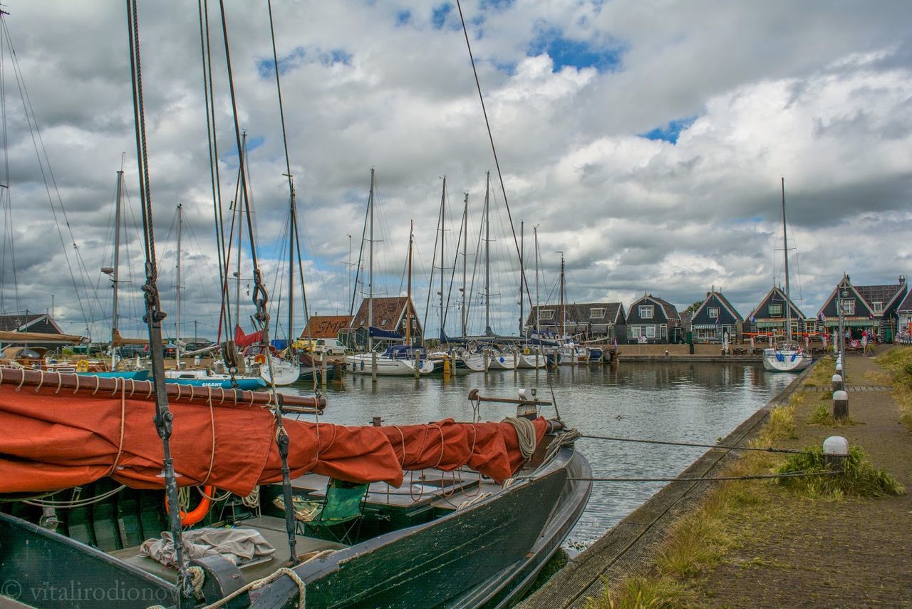 Sailboats moored at harbor against sky