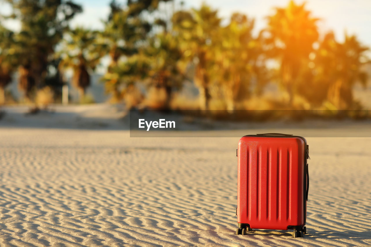 Summer travel and tourist planning vacation. red suitcase in the beautiful sand beach on palms trees