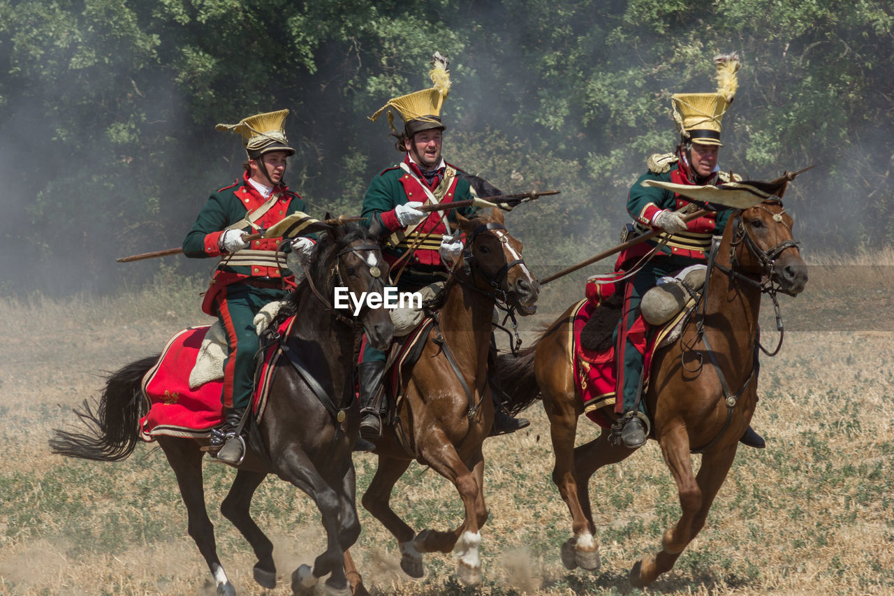 PEOPLE RIDING HORSES ON FIELD