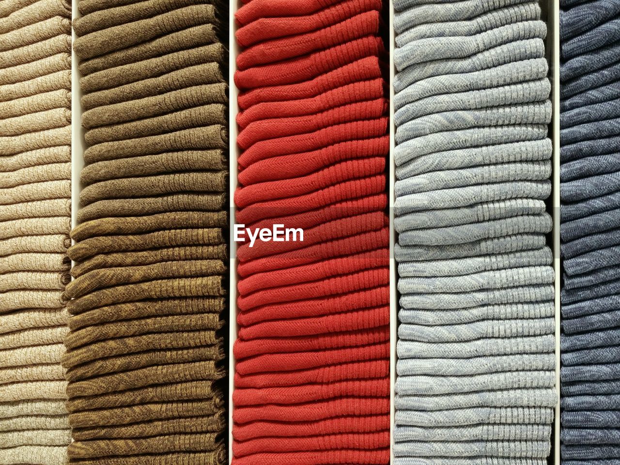 Full frame shot of folded textiles on shelves in store