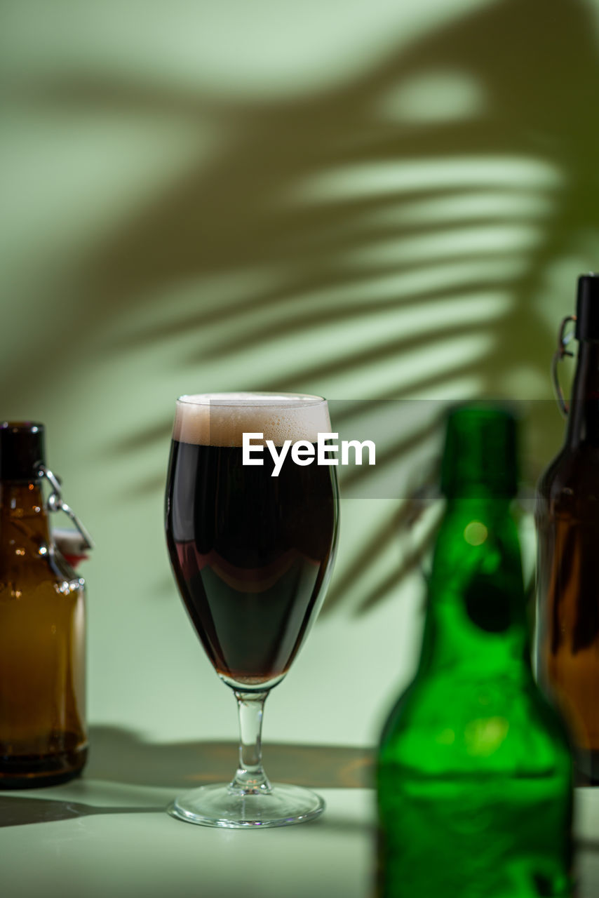 CLOSE-UP OF BEER GLASS WITH BOTTLE ON TABLE