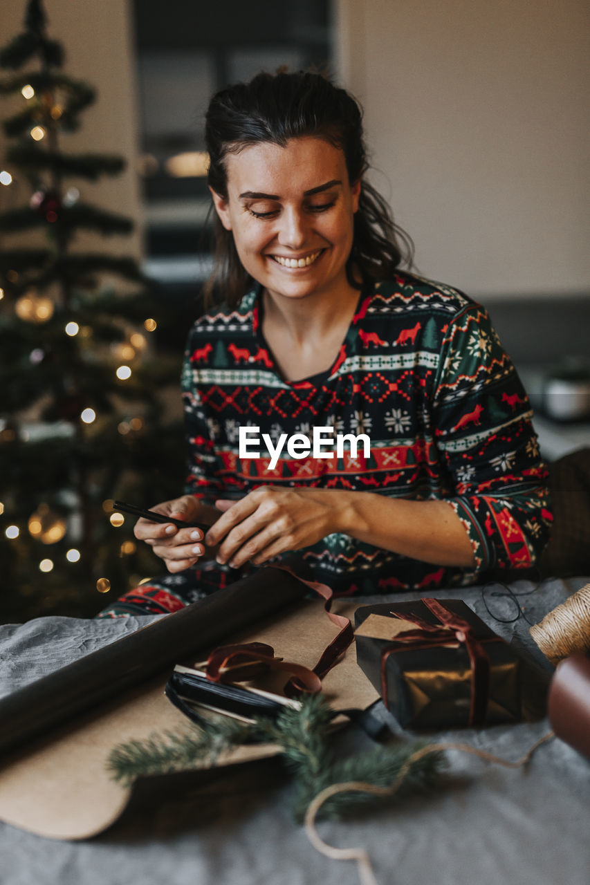 Smiling woman wrapping presents at table