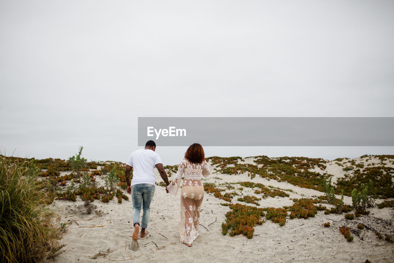 Mixed race couple holding hands walking on beach