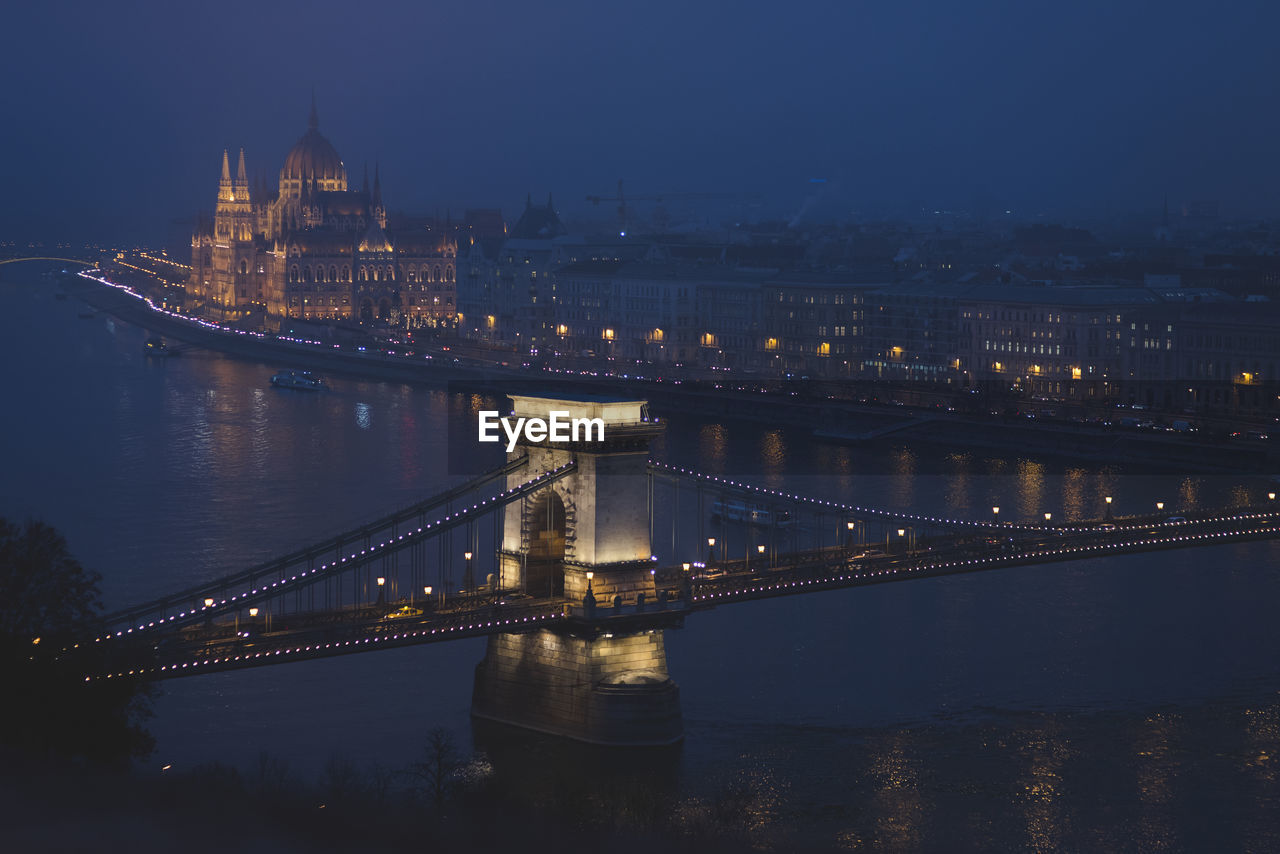 Illuminated chain bridge over river at night