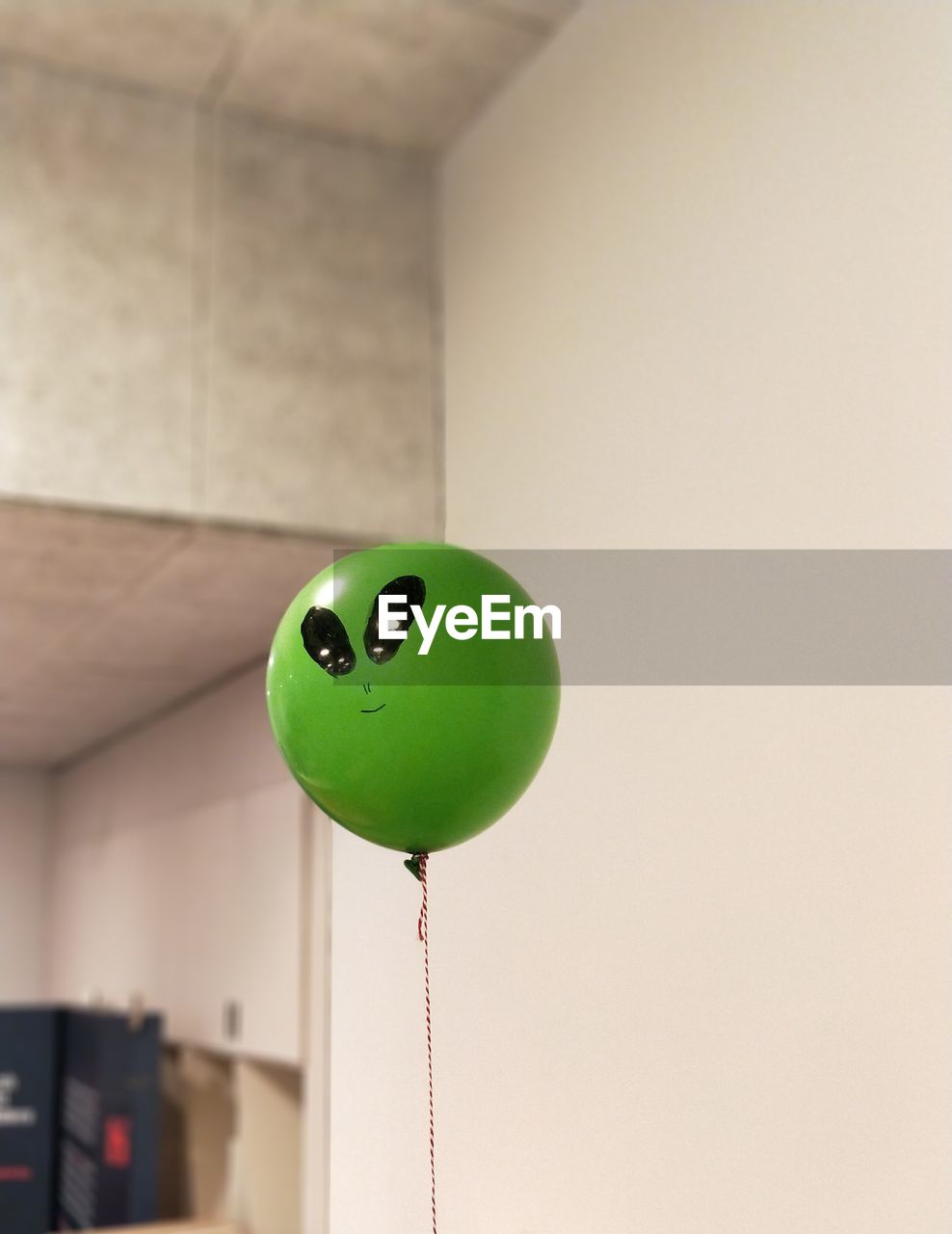 Close-up of green balloon against white wall