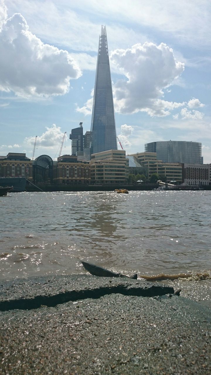 The shard tower by river thames against cloudy sky