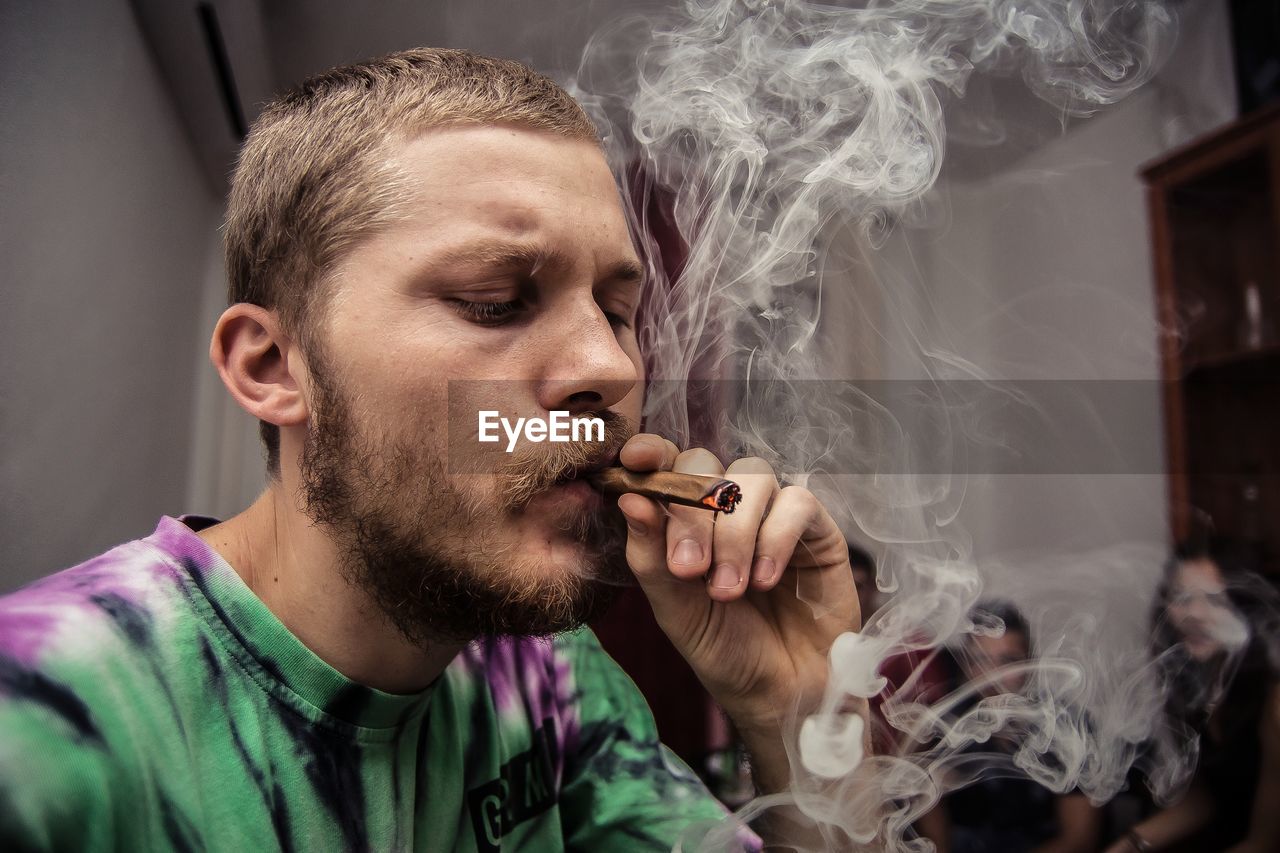 Close-up of young man smoking marijuana joint