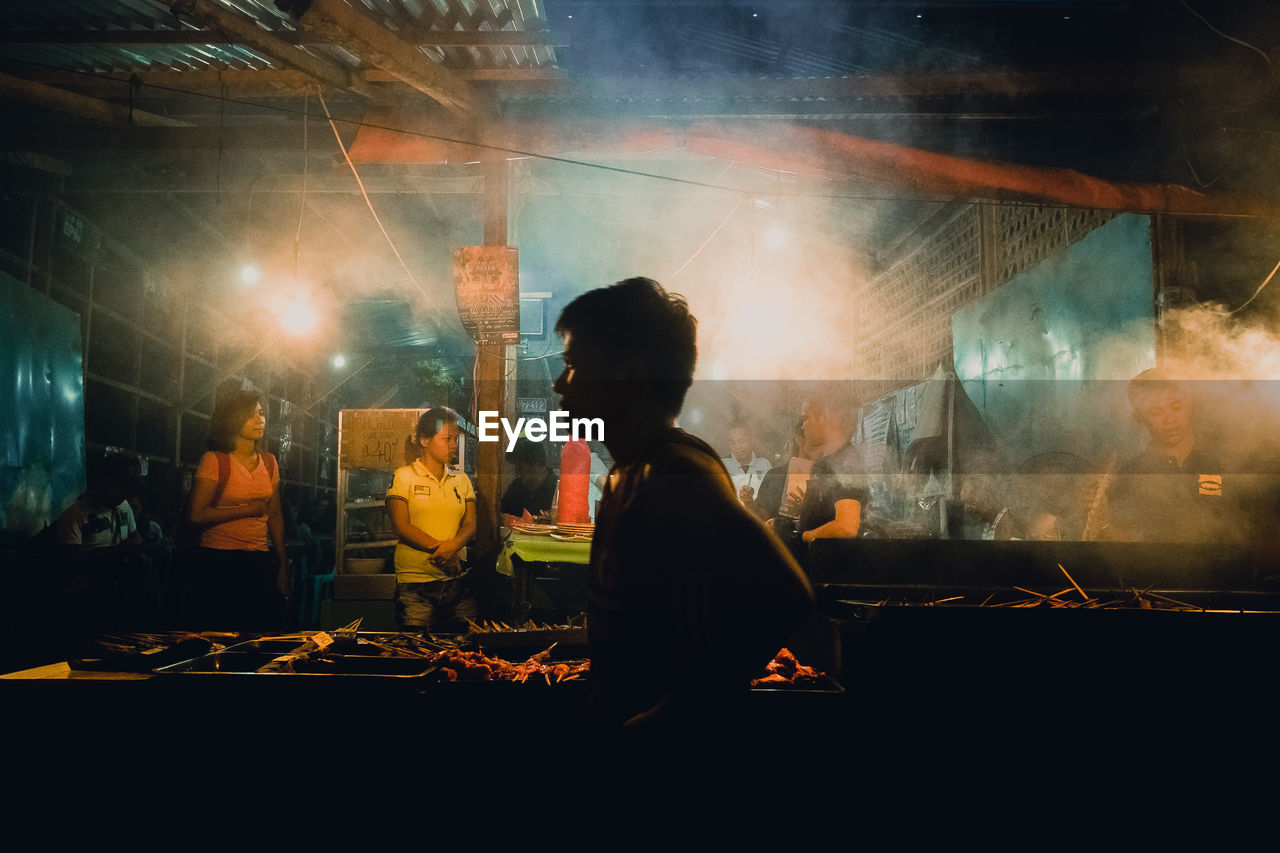 REAR VIEW OF MAN WORKING AT NIGHTCLUB