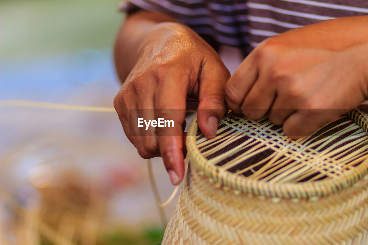 Midsection of man making wicker decoration