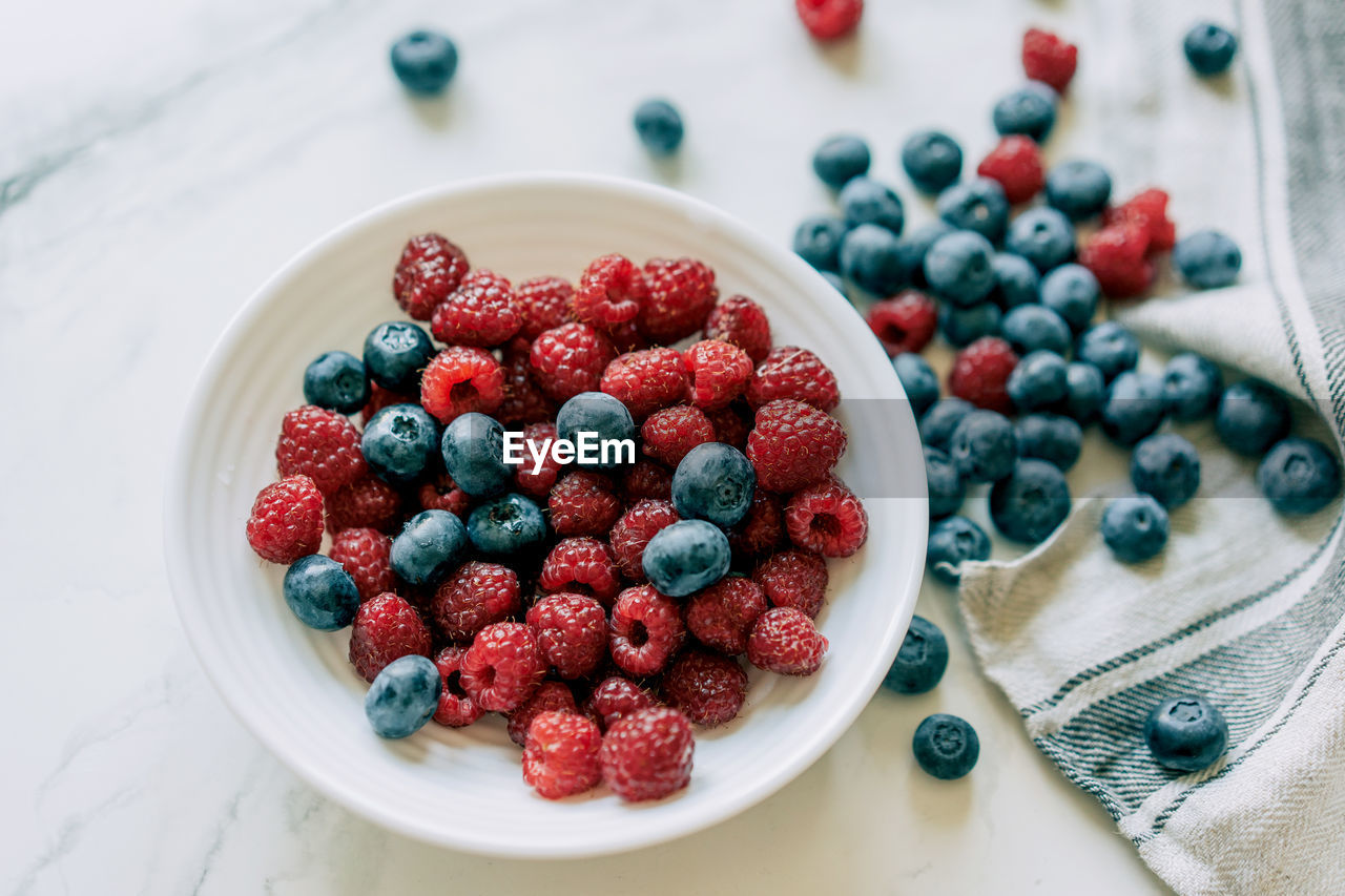 Top view of pile of fresh and healthy and berries for wellness on marble background.