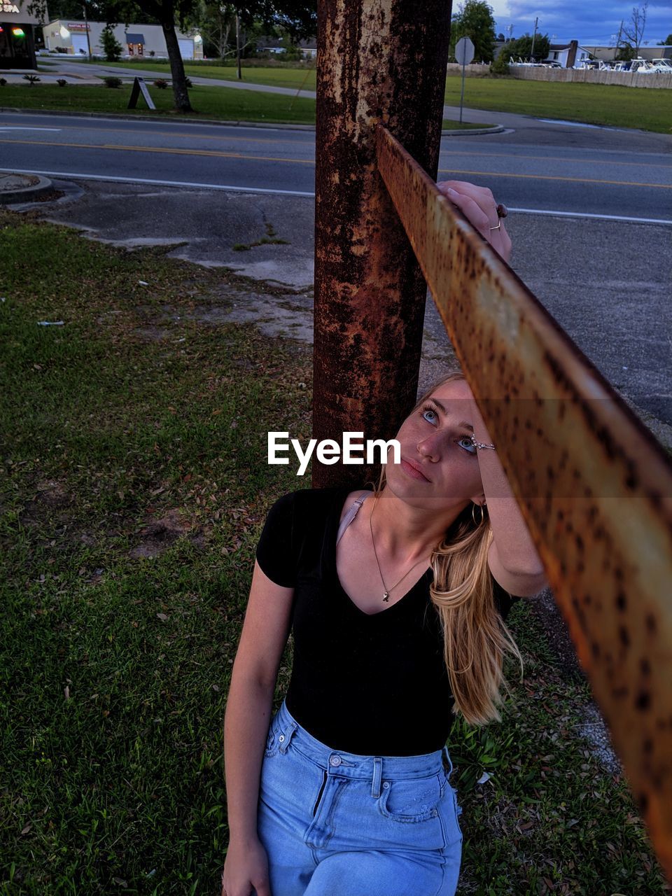 PORTRAIT OF YOUNG WOMAN STANDING ON TREE TRUNK