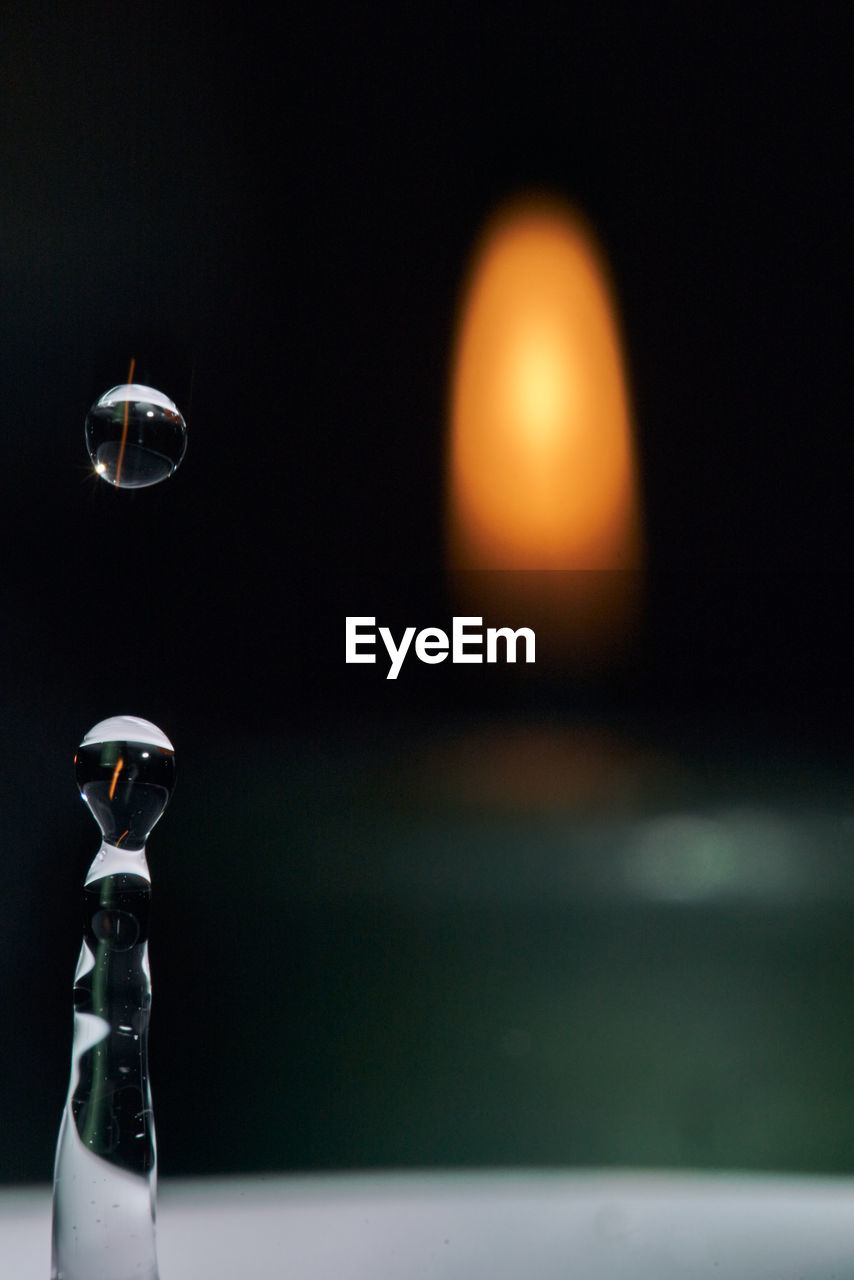 CLOSE-UP OF WINE GLASS AGAINST ILLUMINATED WATER