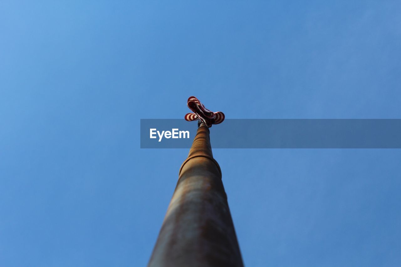 Directly below of flag pole against clear blue sky