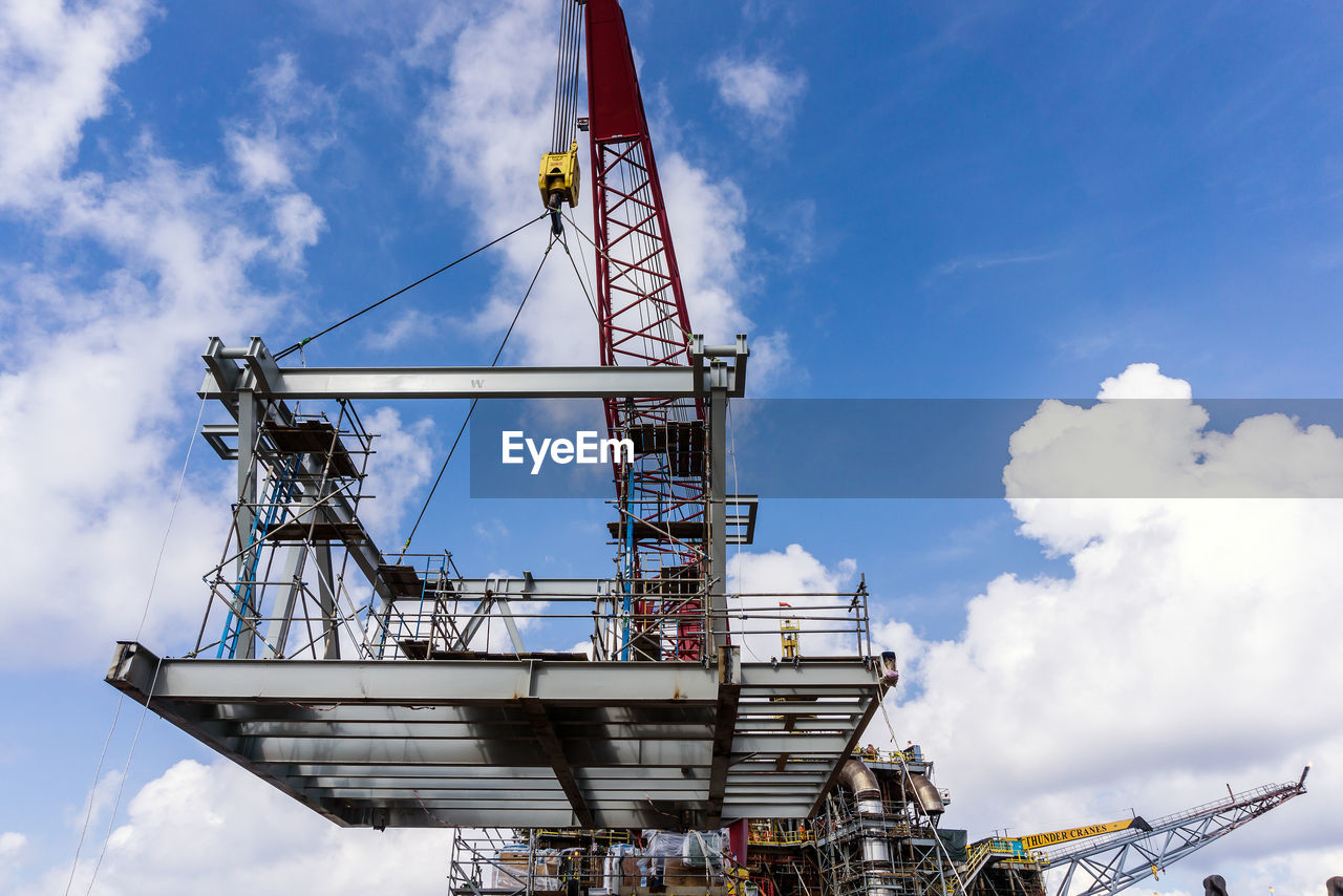 Offshore crane on board a construction work barge performing heavy lifting of a structure frame