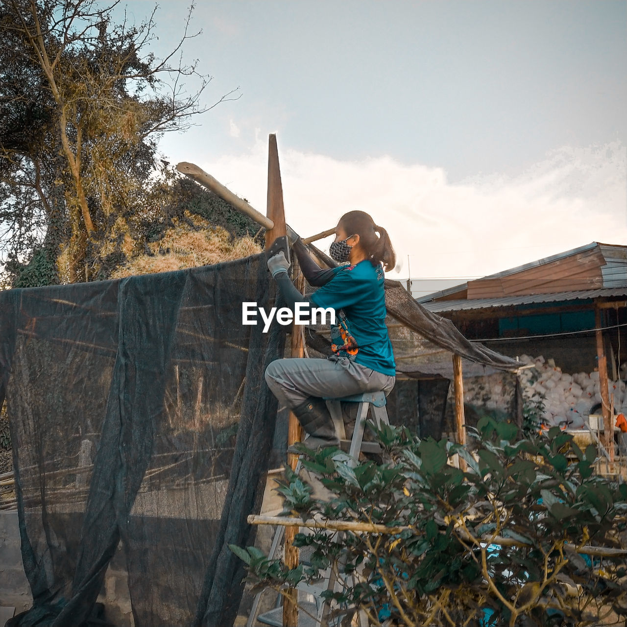 Woman building shed outside house