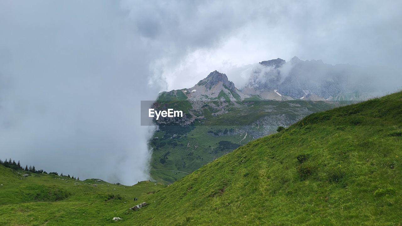 environment, landscape, highland, mountain, cloud, scenics - nature, mountain range, land, sky, beauty in nature, nature, fog, plant, grass, travel, ridge, meadow, travel destinations, plateau, mountain pass, green, tourism, social issues, no people, non-urban scene, mountain peak, outdoors, water, panoramic, overcast, valley, activity, rock, forest, tranquility, wilderness, terrain, environmental conservation, tranquil scene, rural scene, trip, vacation, tree, day, grassland, field, plain, holiday, cliff