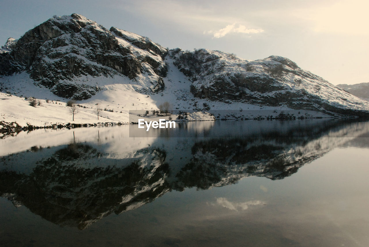 Scenic view of lake by snowcapped mountains against sky