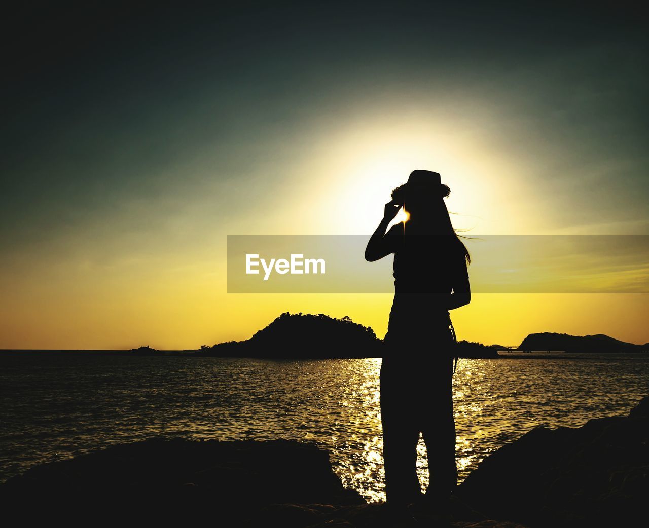 SILHOUETTE MAN STANDING ON SHORE AGAINST SKY DURING SUNSET