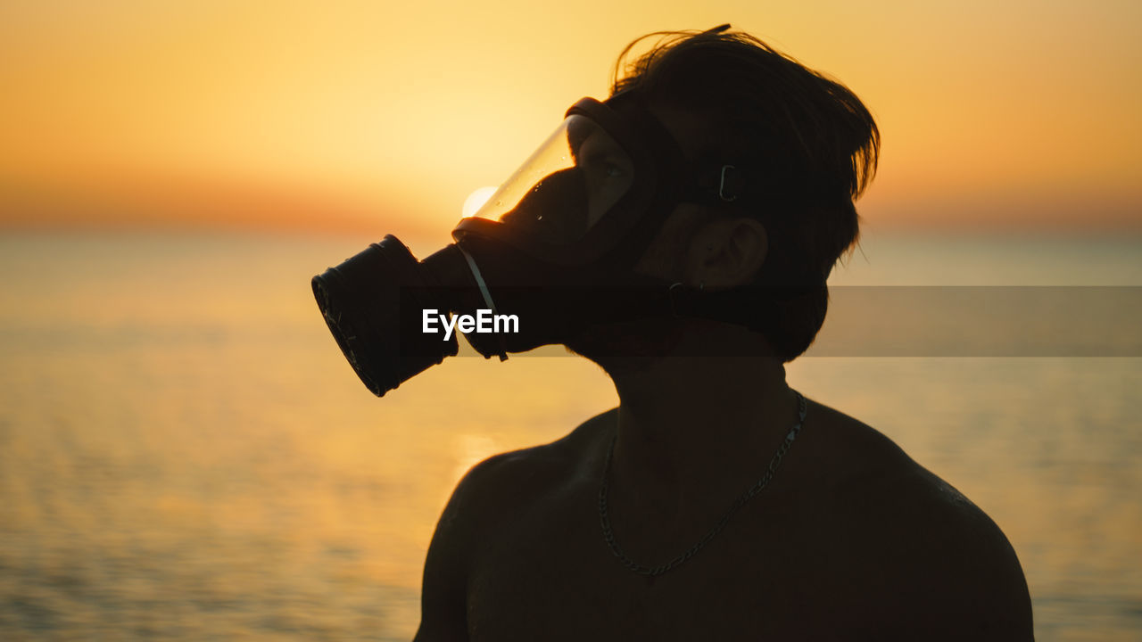 Man with gas mask at sunrise