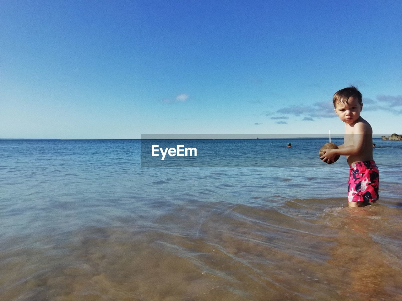 Full length of shirtless boy in sea against blue sky