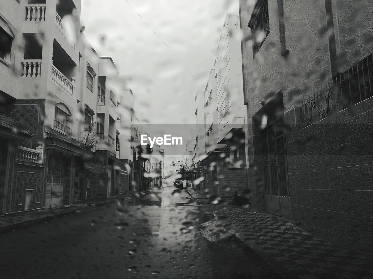 Wet street amidst buildings in city