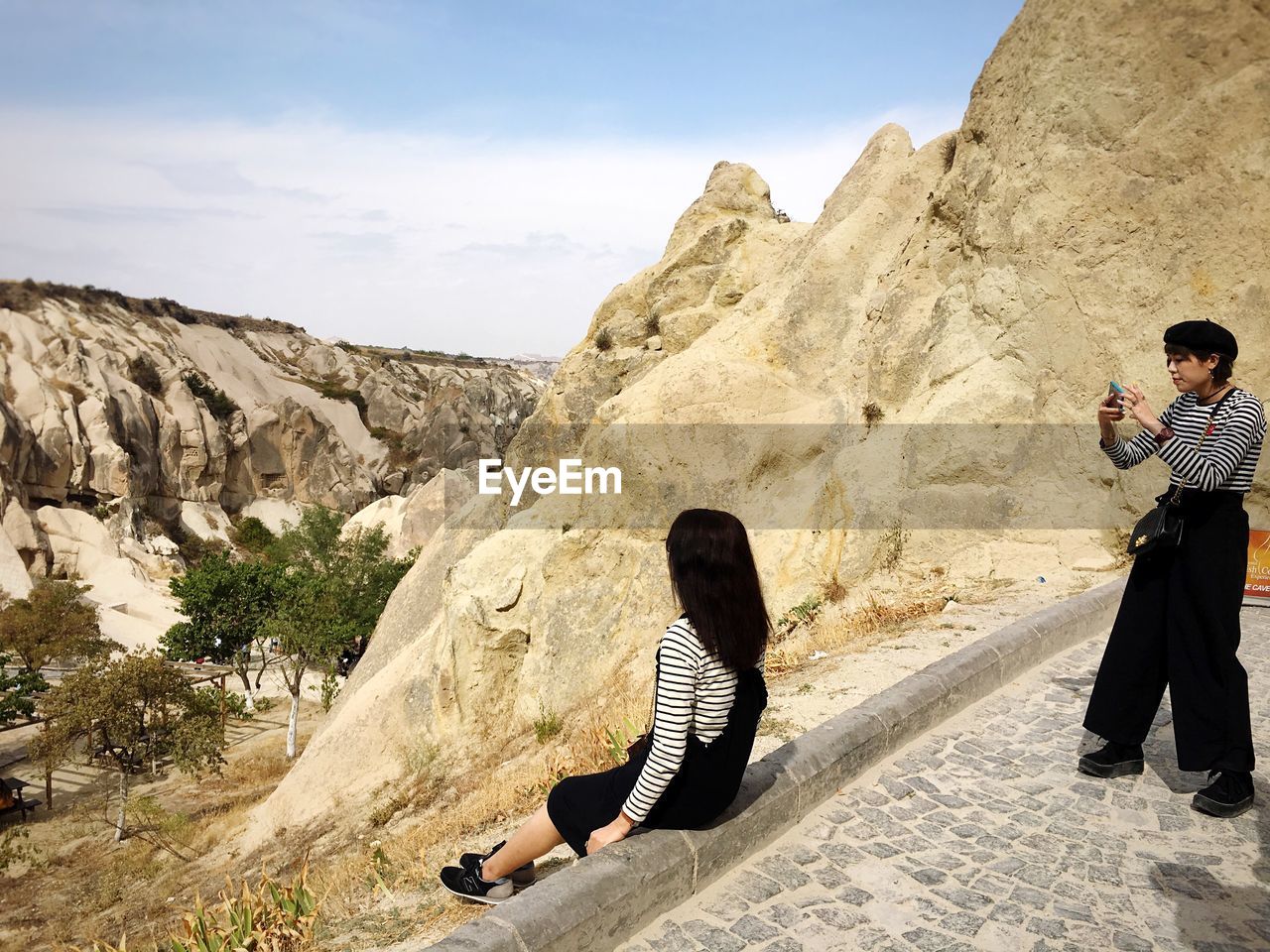 REAR VIEW OF COUPLE SITTING ON ROCK