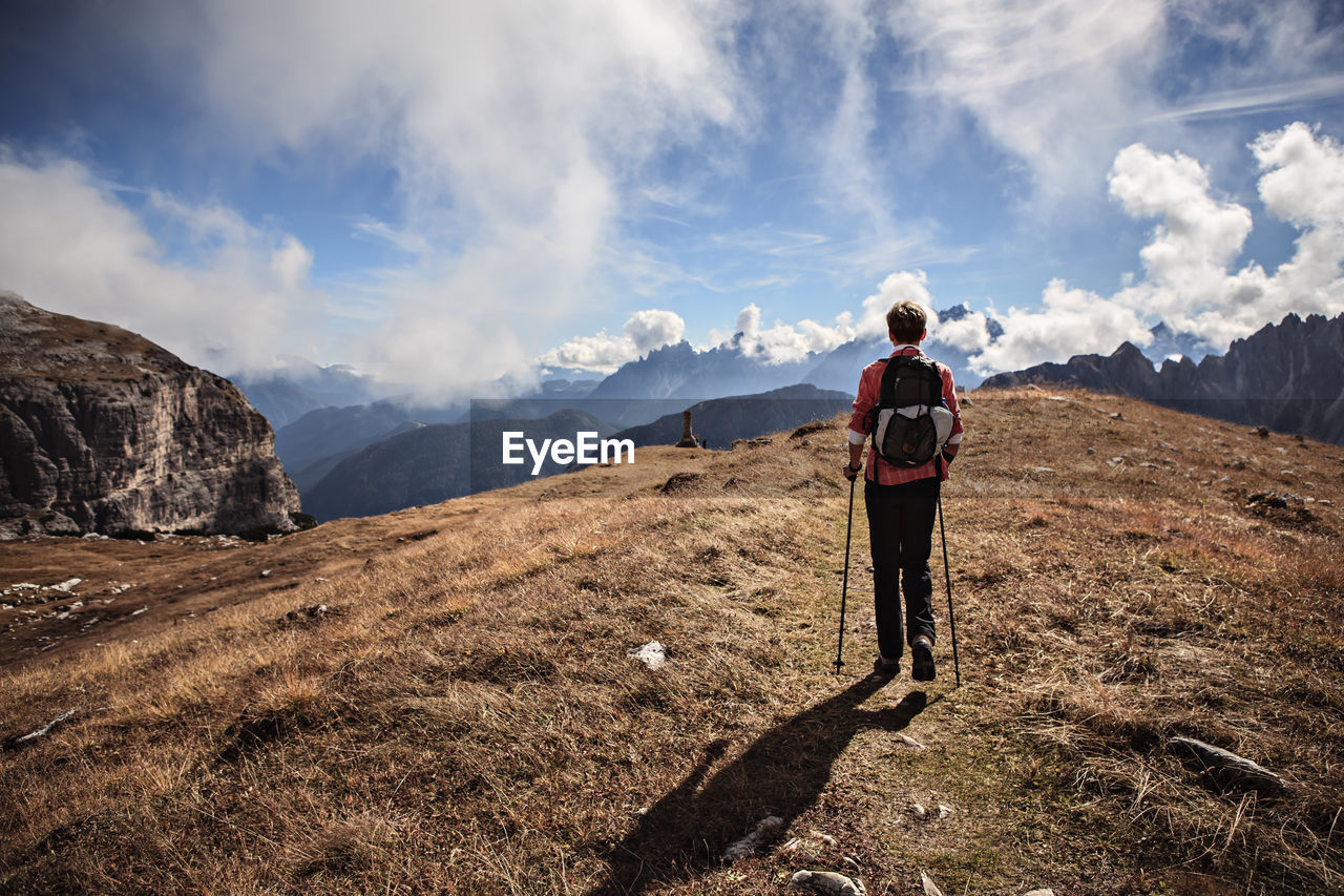 Rear view of woman standing on mountain against sky