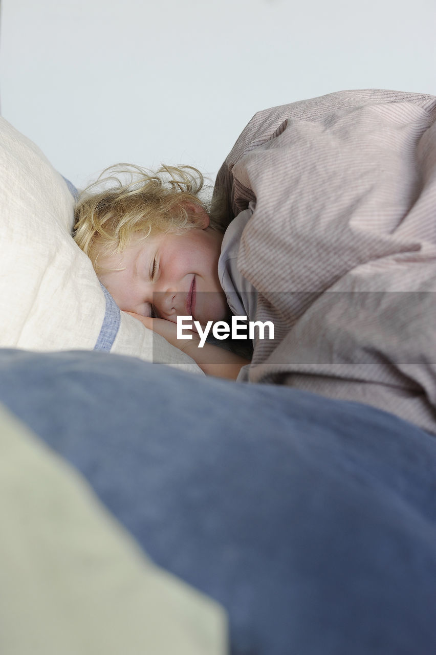 Smiling girl with eyes closed relaxing in bed