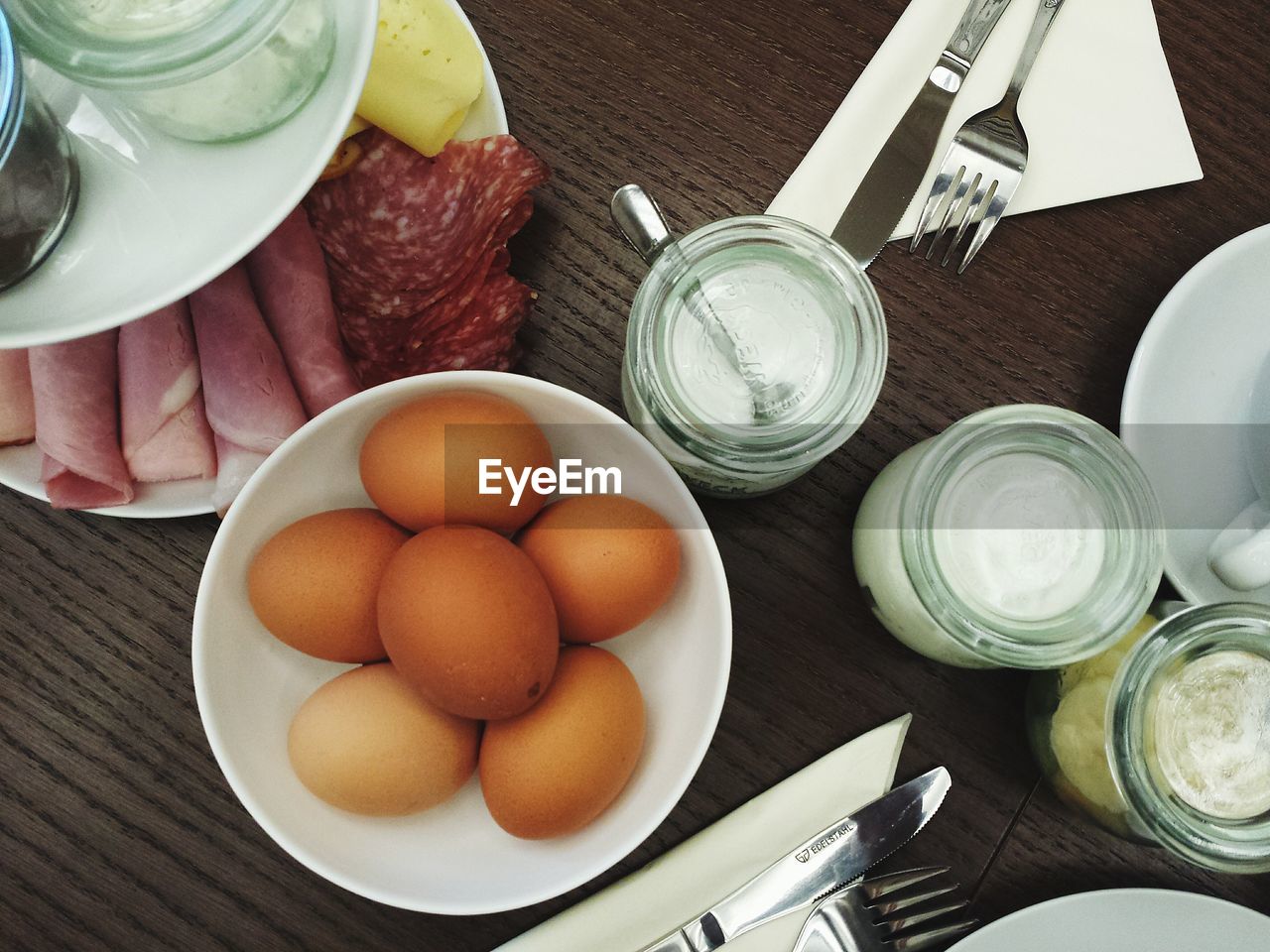 Directly above shot of eggs and meat and jars on table