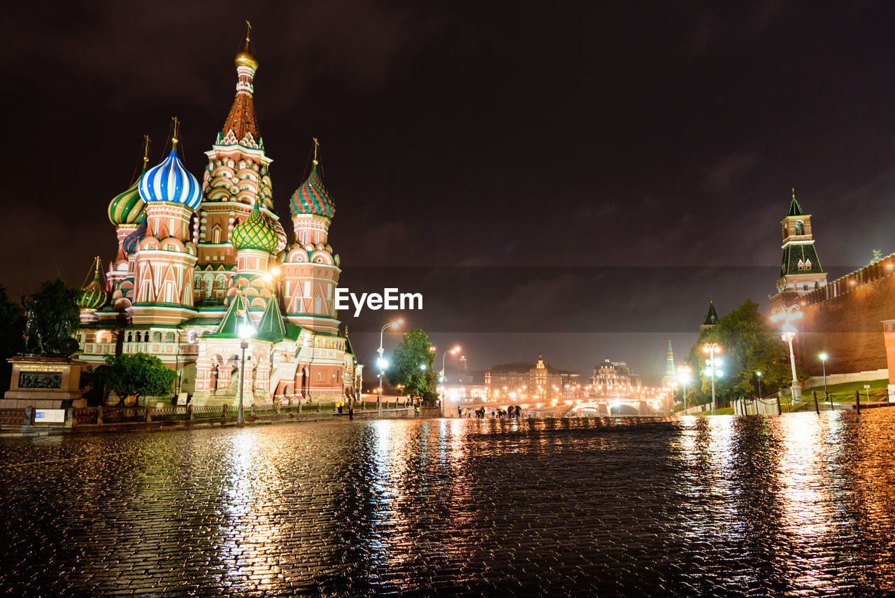 Illuminated saint basils cathedral by lake at night