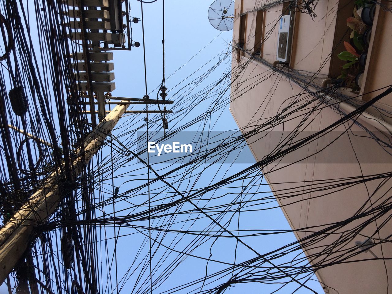 Low angle view of power lines against house