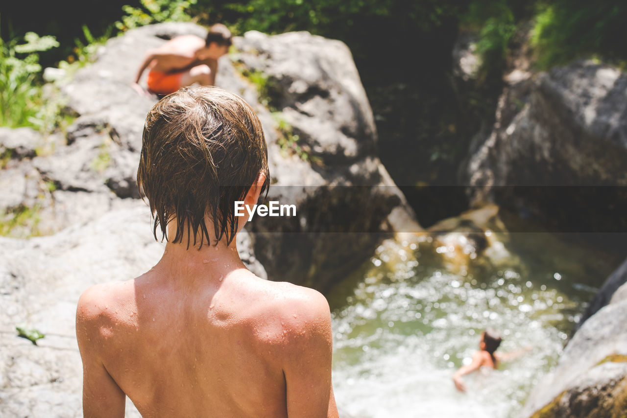 Rear view of shirtless boy in water