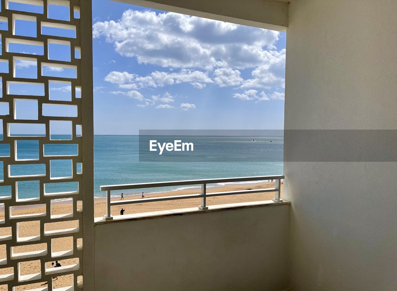 sky, sea, water, cloud, window, horizon, nature, horizon over water, interior design, architecture, day, wall, scenics - nature, blue, window covering, no people, outdoors, beauty in nature, beach, home, land, sunlight, built structure, room, house, building, tranquility, travel, glass, tranquil scene, railing