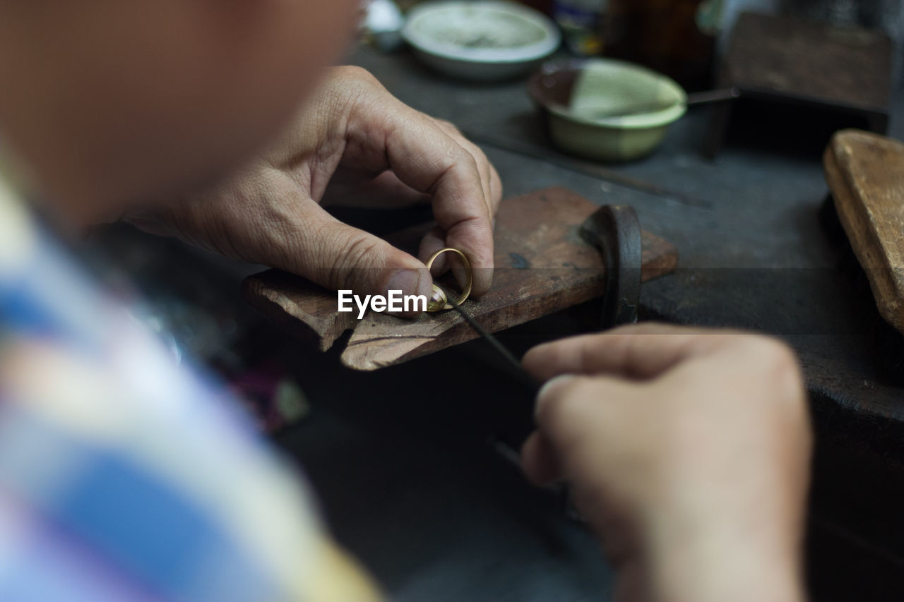 Midsection of man working on jewelry in workshop