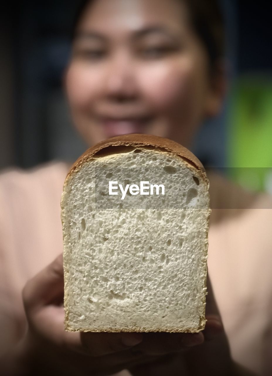 one person, bread, food and drink, holding, food, portrait, adult, indoors, close-up, focus on foreground, women, baked, young adult, headshot, front view, emotion, wellbeing, freshness, selective focus