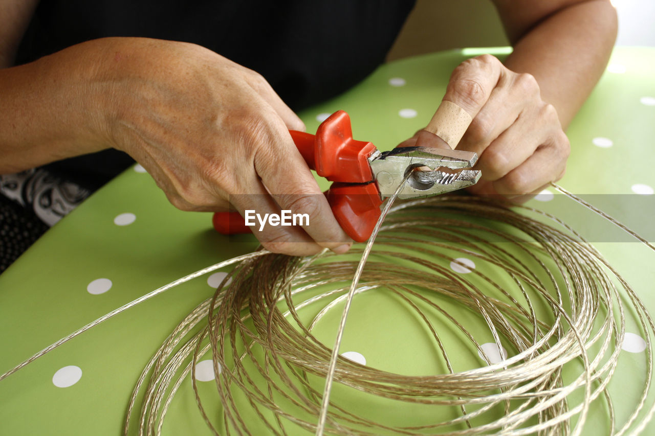 Midsection of woman cutting cable on table