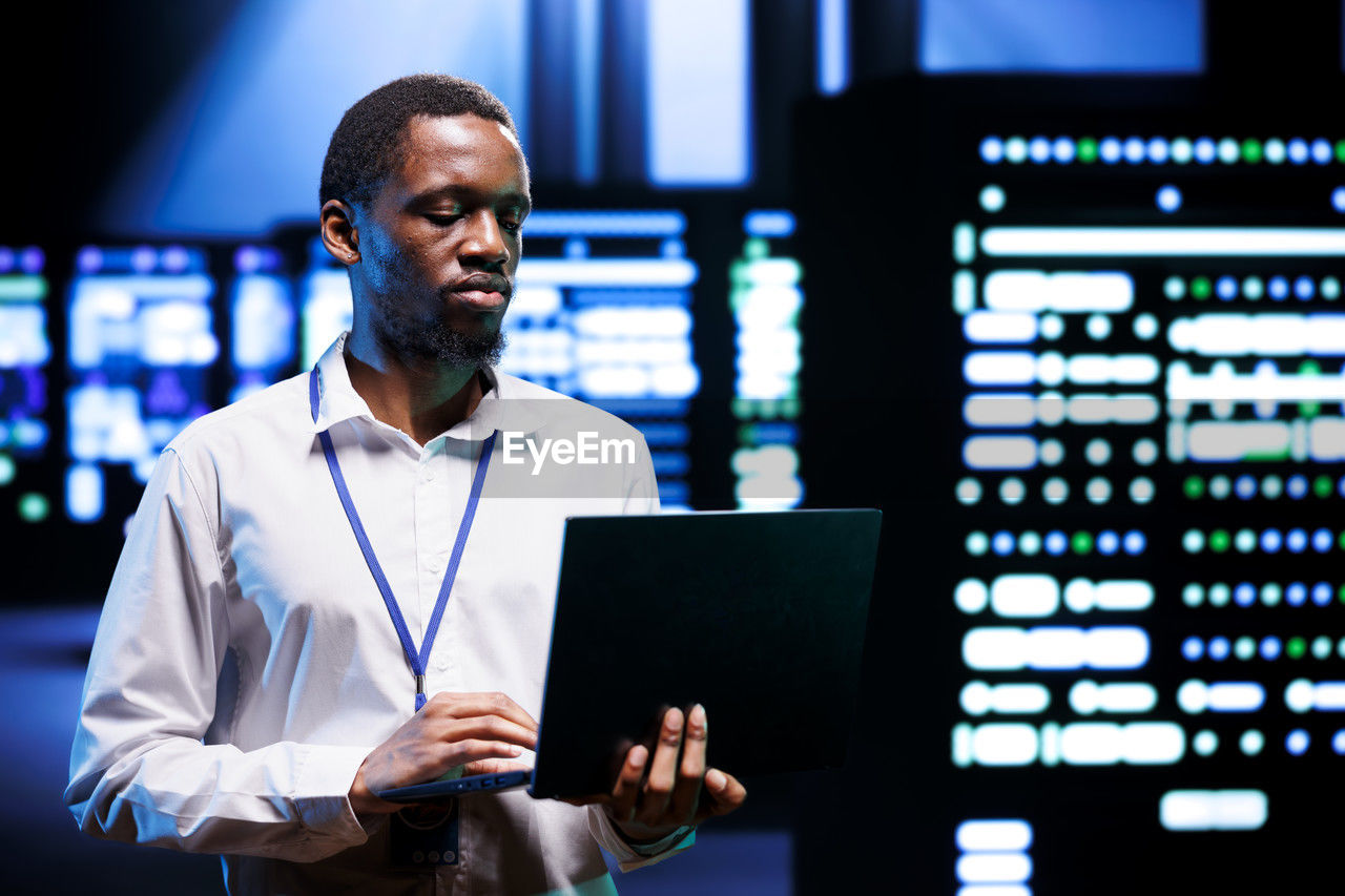 side view of young man using laptop while standing in cafe