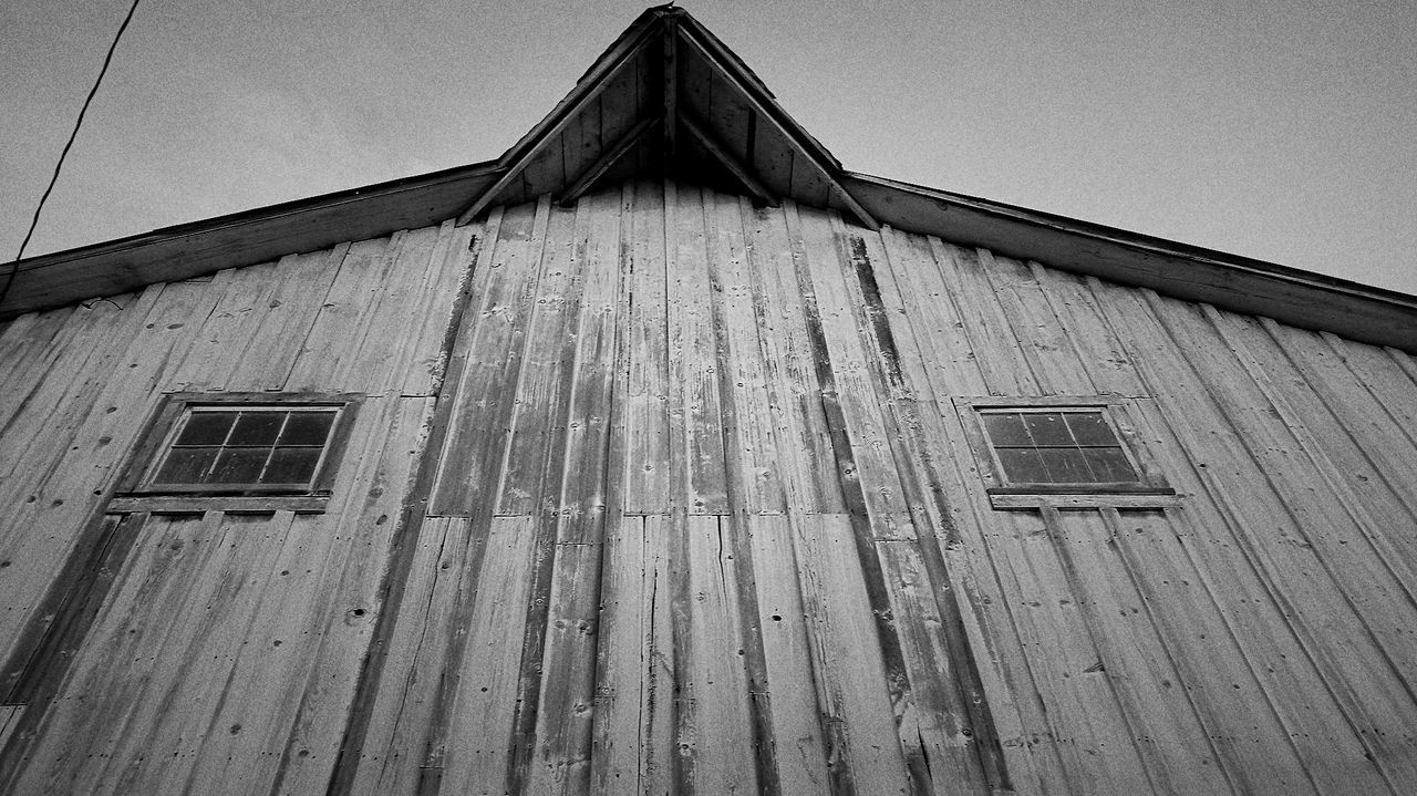 LOW ANGLE VIEW OF BARN ON ROOF AGAINST SKY