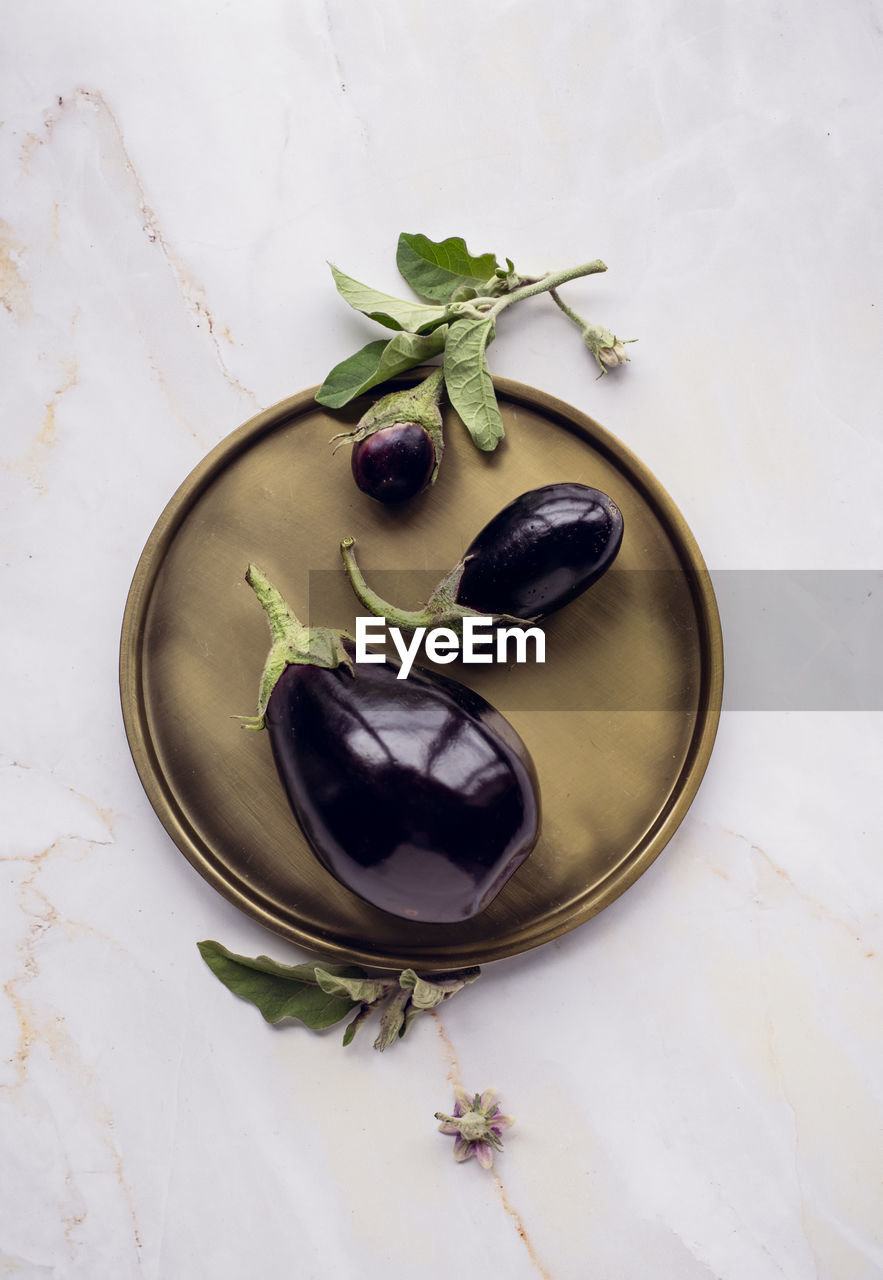 Beautiful minimalistic composition of eggplants on dish , marble background.