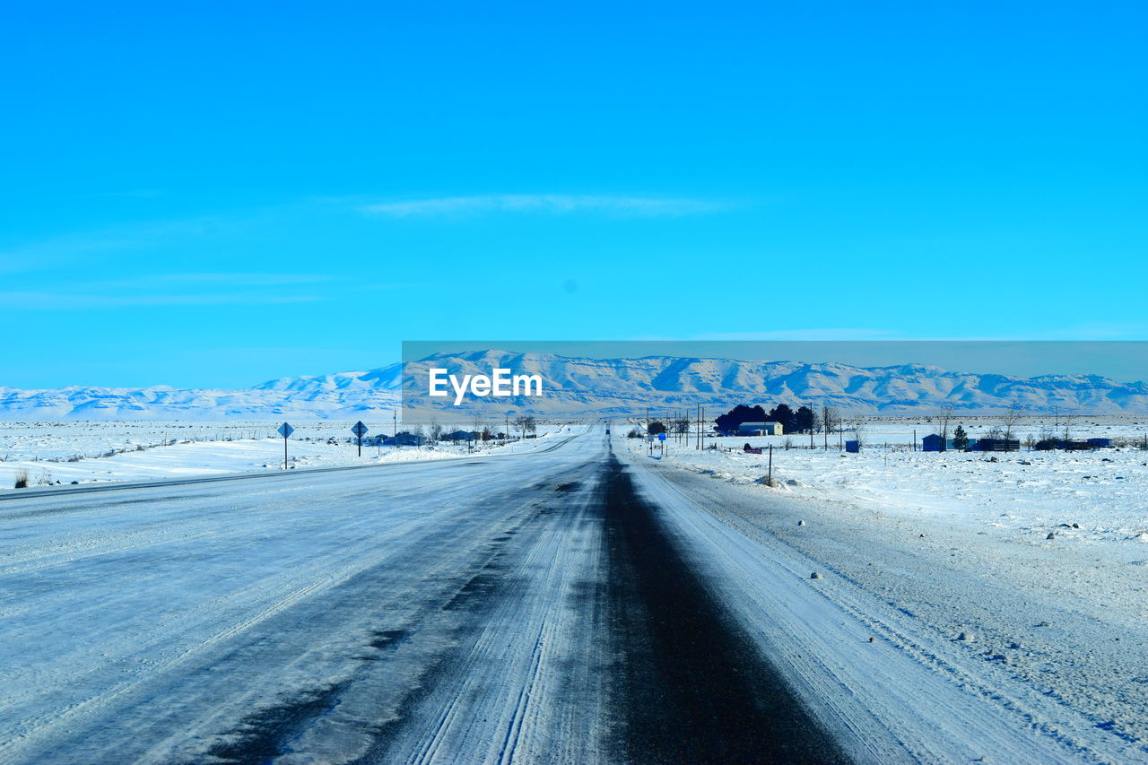 Tire tracks on snow landscape against blue sky