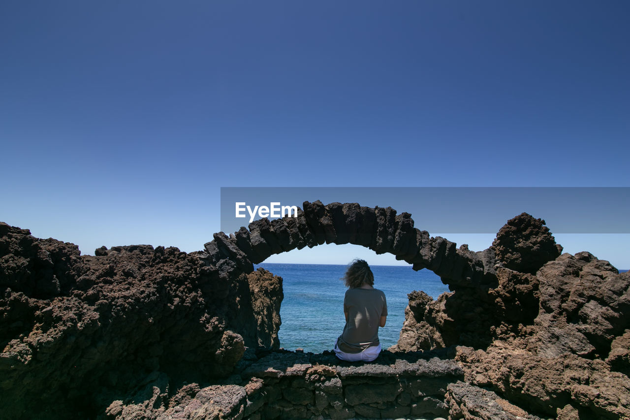 Rear view of woman looking at sea against clear sky