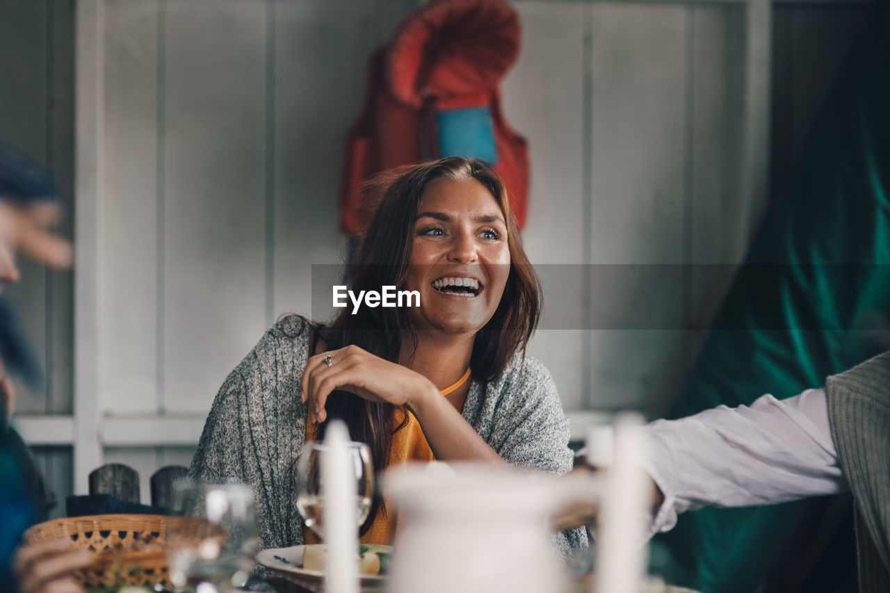 Cheerful young female friends sitting at dining table